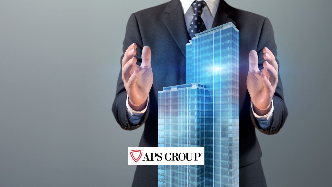 Businessman in a suit standing with hands around two tall glass office buildings, with the APS Group logo on the left side, representing professional facility management services